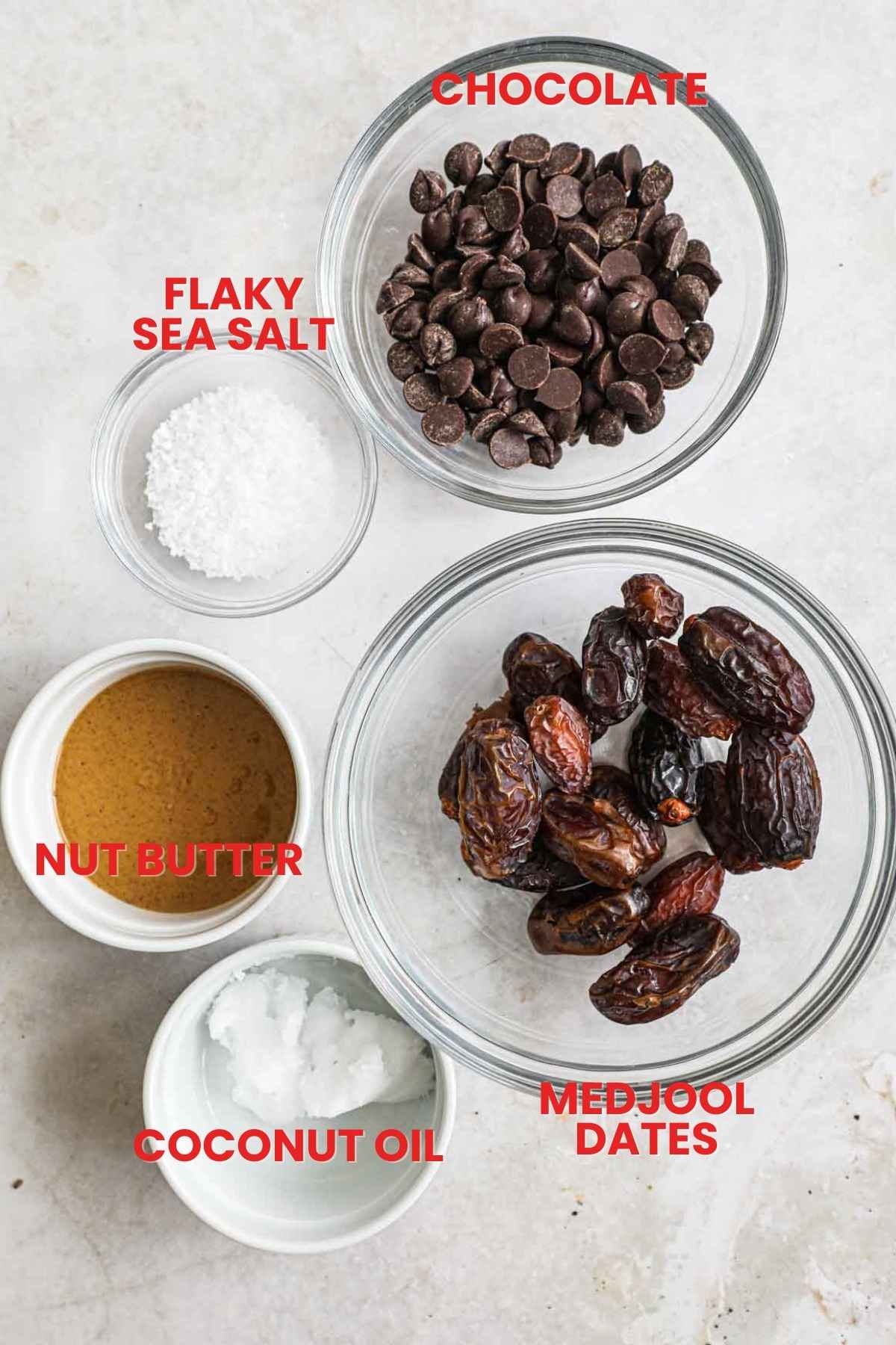 Ingredients to make chocolate covered vegan dates, including chocolate, medjool dates, nut butter, flaky sea salt, and coconut oil.